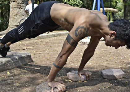 Athletic man performing elevated push-ups on rocks in a park setting.